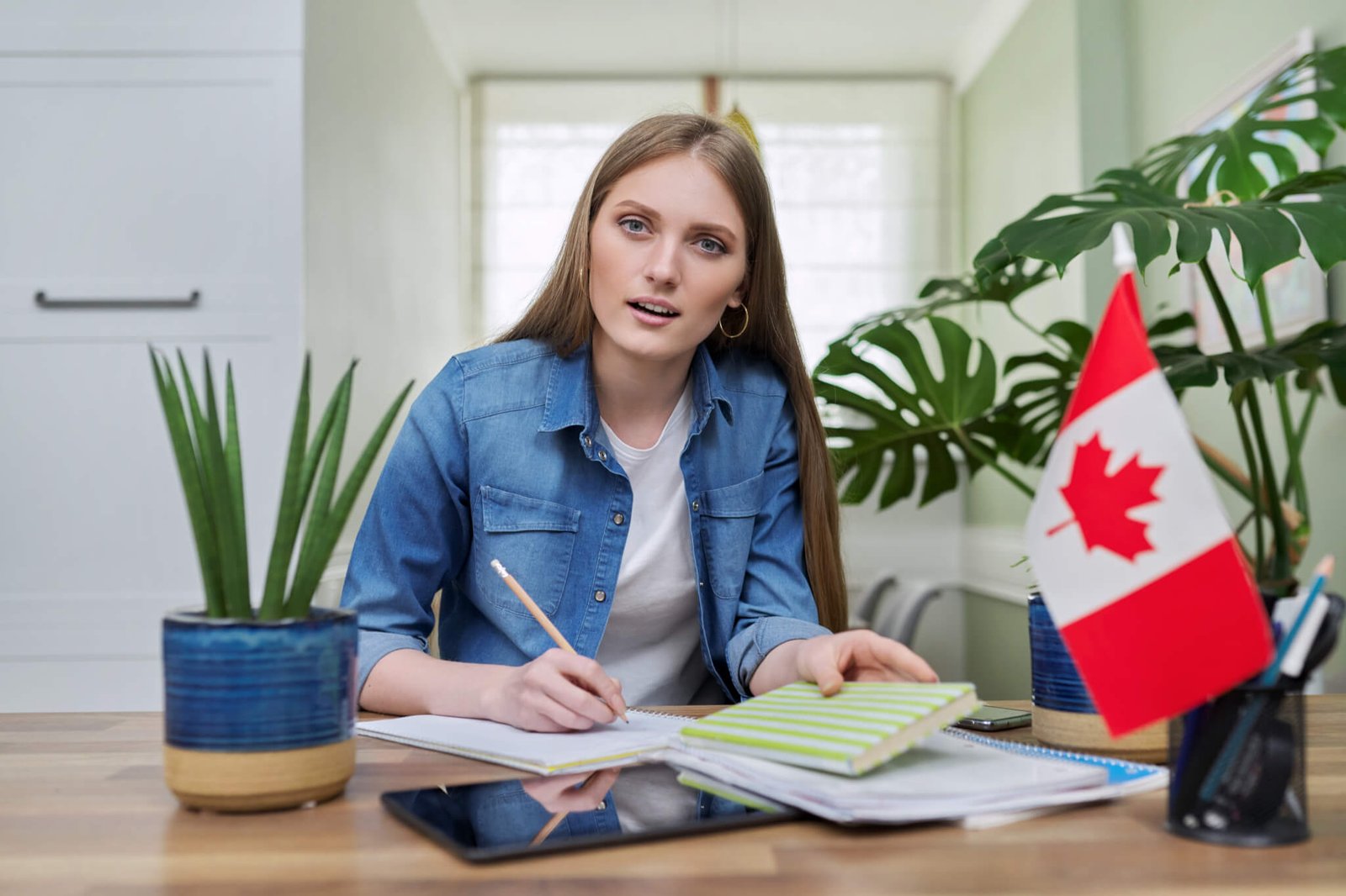 online-training-female-teenager-sitting-at-home-looking-at-webcam-canadian-flag-on-table.jpg